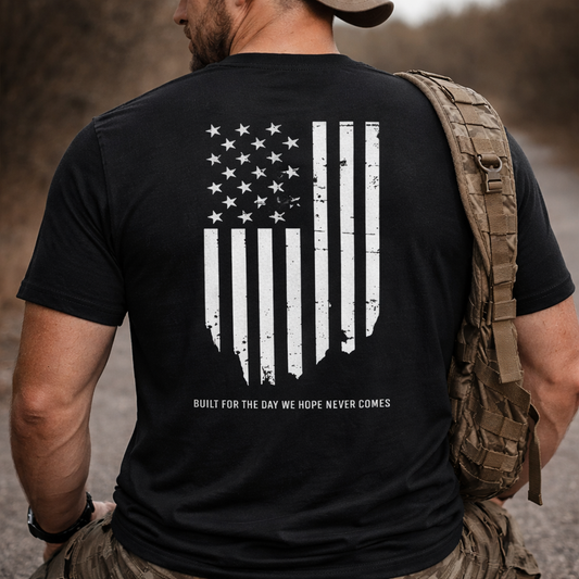 Person wearing a black t-shirt with an American flag design and text, standing outdoors.