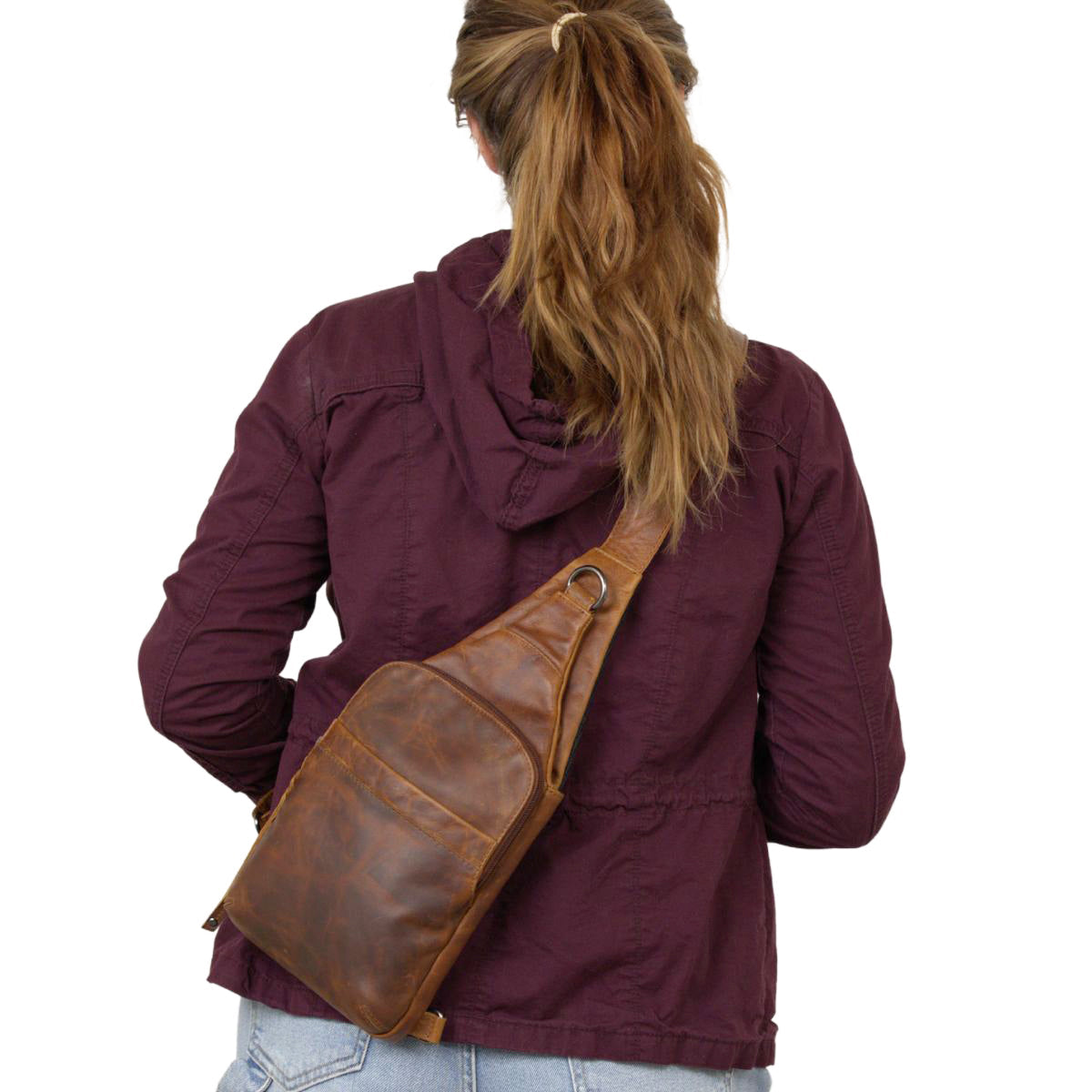 Person wearing a brown leather sling bag over one shoulder on a white background