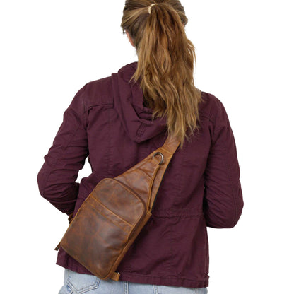 Person wearing a brown leather sling bag over one shoulder on a white background