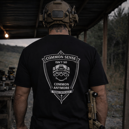 Person wearing a black t-shirt with a graphic design and text, standing outdoors.