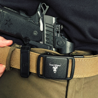Close-up of a gun in a holster on a person's belt with a tactical belt.