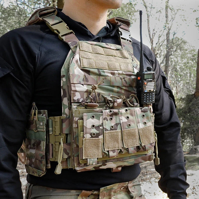 Person wearing a camouflage tactical vest with a walkie-talkie in an outdoor setting